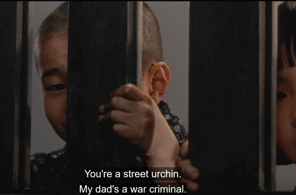 a close up image of a child hiding behind bars. Subtitles below the child read 'You're a street urchin. My dad's a war criminal."