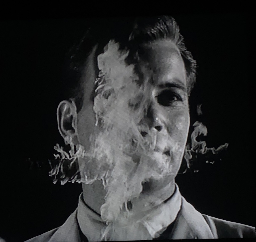 Close-up of a man with a burning cross superimposed over his face.