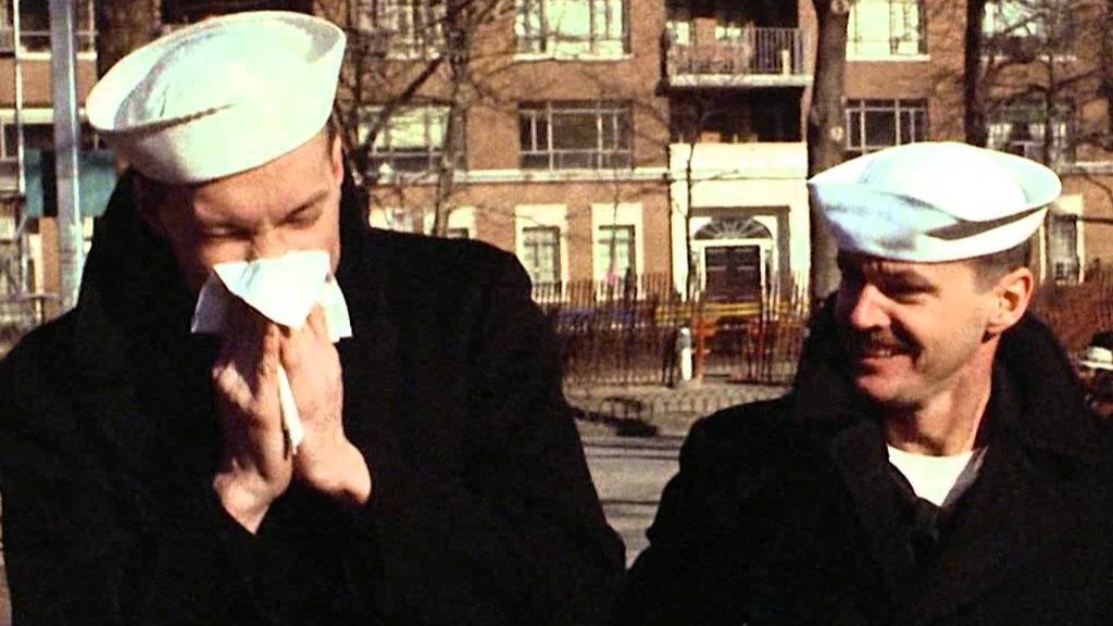 Two sailors walking, one is sneezing, one is smirking