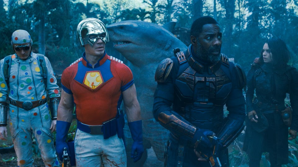 A smaller lineup of super heroes standing in a foggy forest. From left to right: Polka Dot Man, Peacemaker, King Shark, Bloodsport, and Ratcatcher II.
