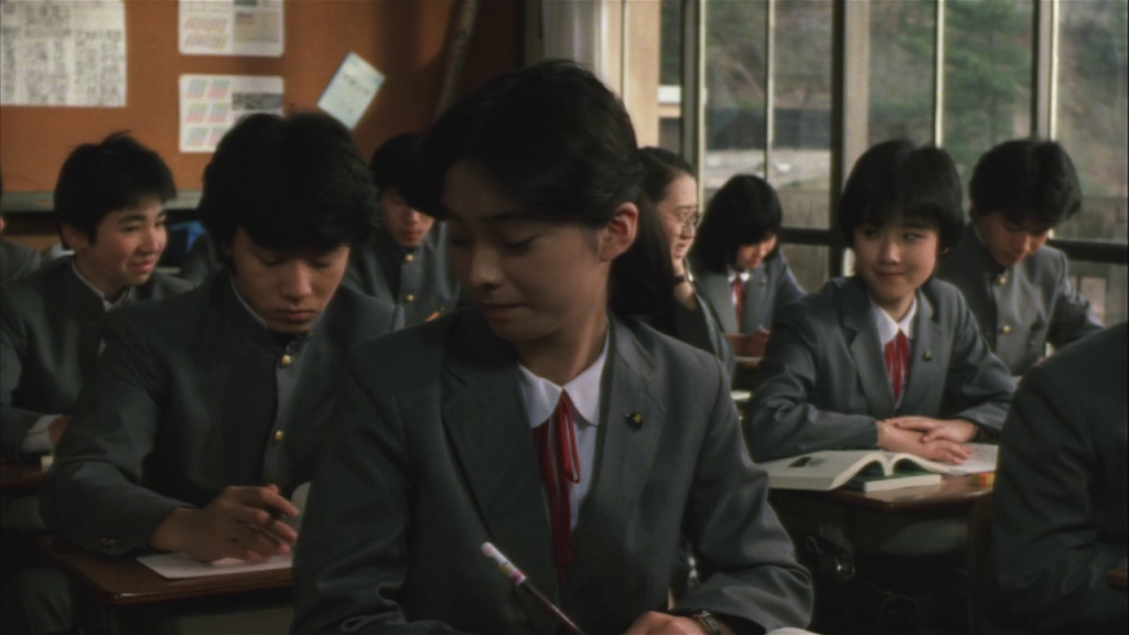 A classroom full of uniform-wearing students in a Japanese school.