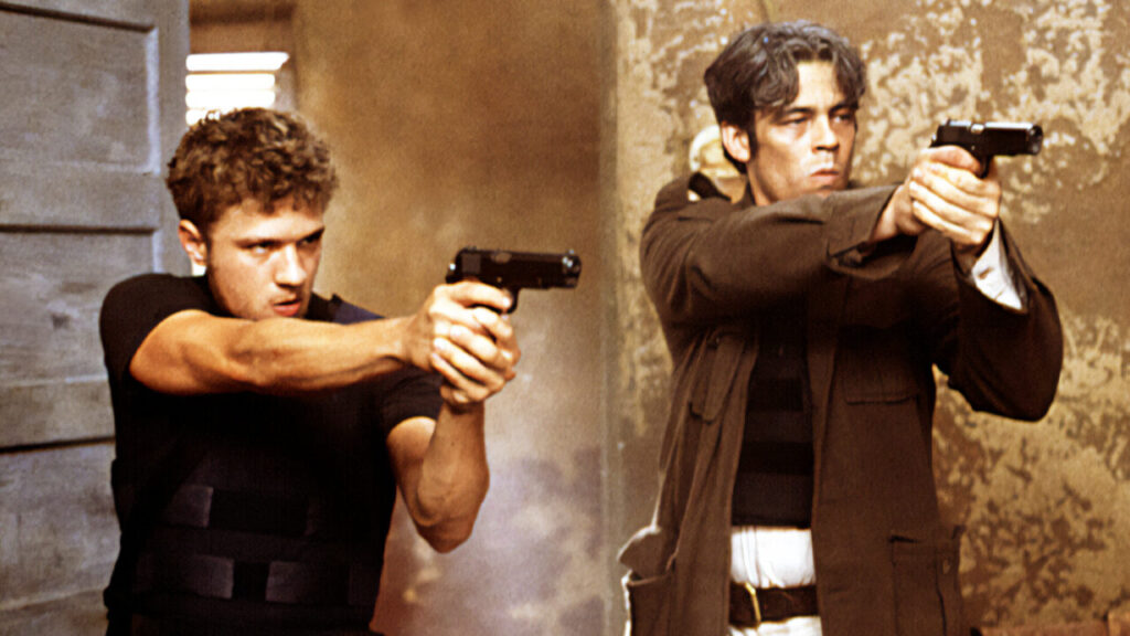 Philippe and Del Toro as Parker and Longbaugh with guns drawn