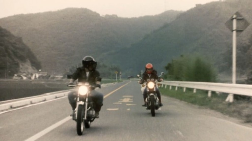 Ko and Fuyumi ride together. The space around them is in color, while the outer frame is in black and white.