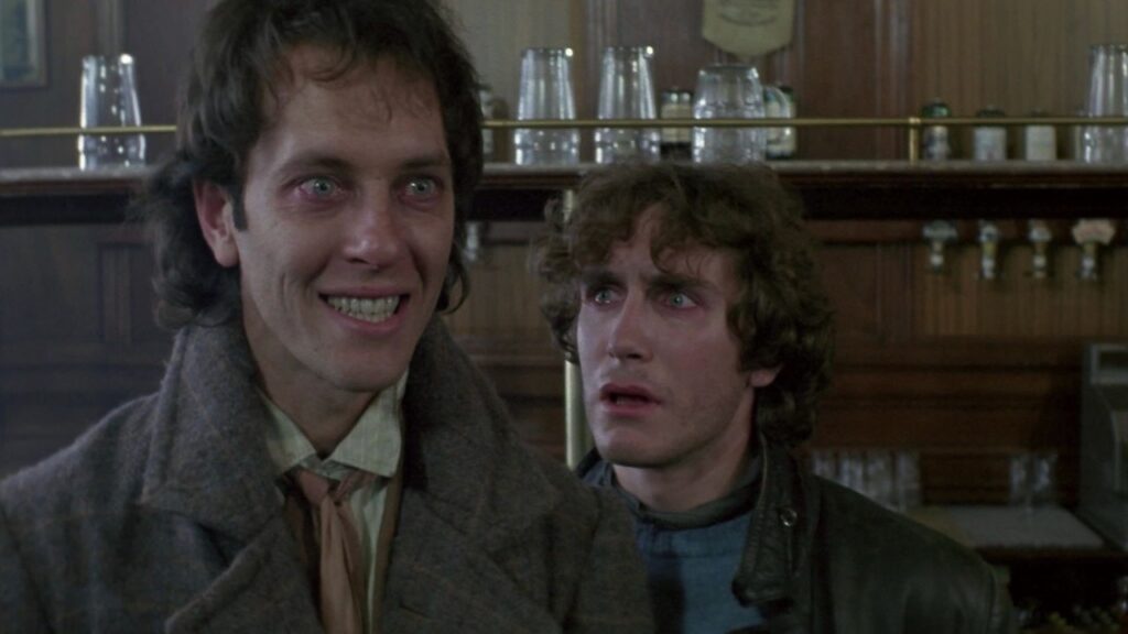 Withnail (Richard E. Grant) nervously smiling while Marwood (Paul McGann gives him a shocked look.