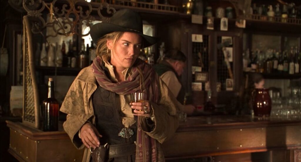a white blonde woman leaning against a bar and holding a glass of beer
