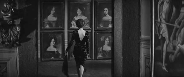  black-and-white image of a woman looking at several paintings on a wall