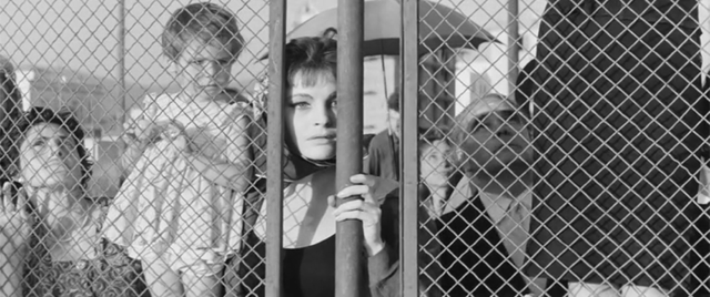 black-and-white image of a woman and a child standing behind a fence