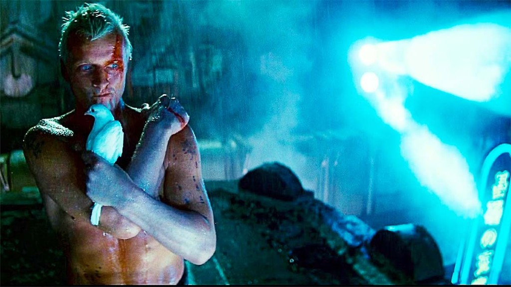 A shirtless Roy Batty (Rutger Hauer) holds a dove on a rainy rooftop