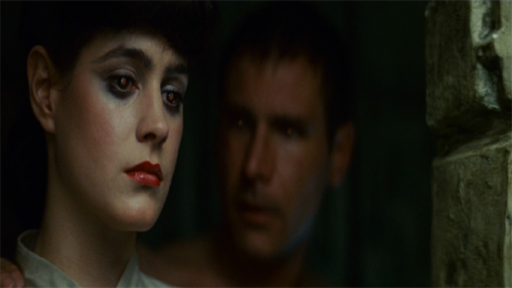 Rick Deckard (Harrison Ford) stares at Rachael (Sean Young) who is looking off-camera. Both their eyes glow faintly orange.