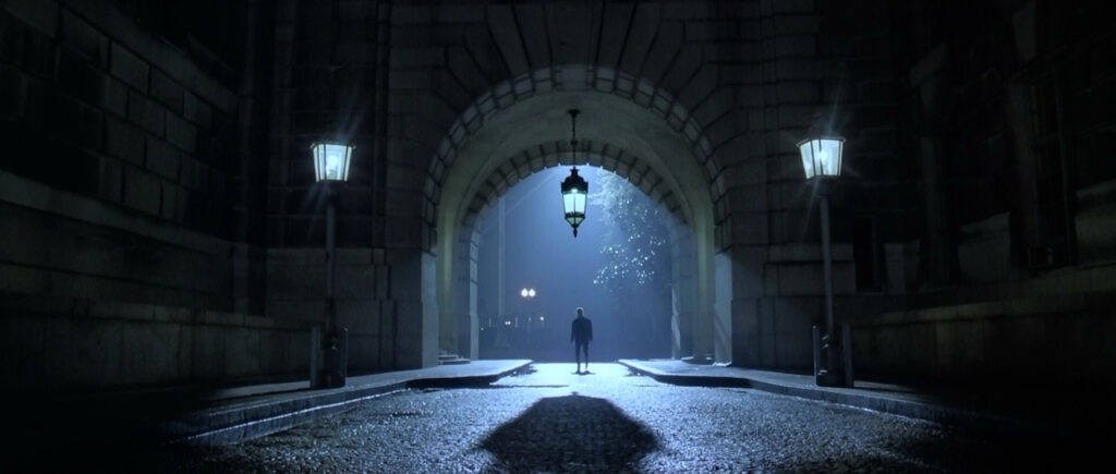  Man standing in underpass lit by street lamps.