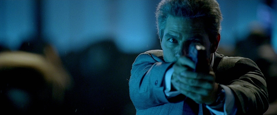  Medium Close Up of Tom Cruise aiming a gun past the camera in a blue tinted nightclub.