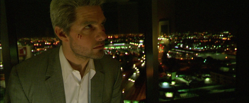 Medium Close Up of Tom Cruise in the upper level of an office building at night. He has blood on his cheek and he's looking peeved.