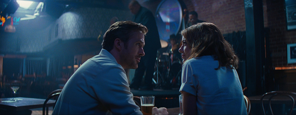 Medium Wide of Emma Stone and Ryan Gosling sitting at a table in a Jazz club.