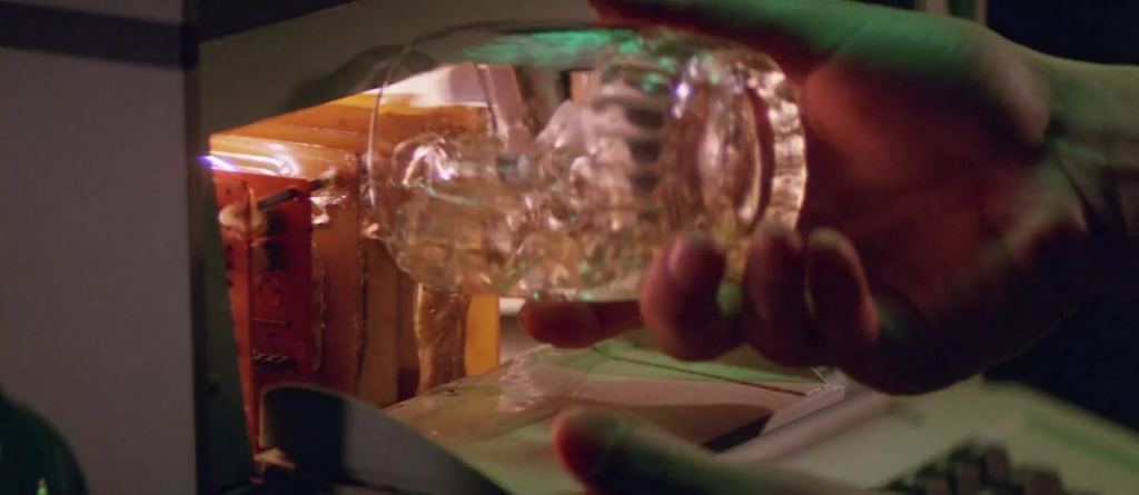 A glass of whisky is turned sideways into a computer, its contents causing a small electrical fire within the device.
