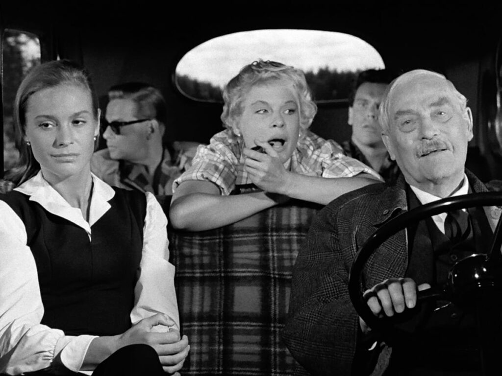 Marianne (Ingrid Thulin), the hitchhikers, and Professor Isak Borg (Victor Sjöström) riding in the car.