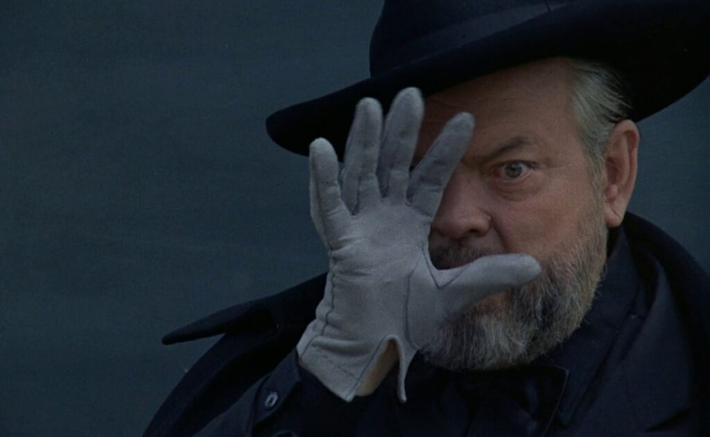 A man partially obscures his face with his hand.