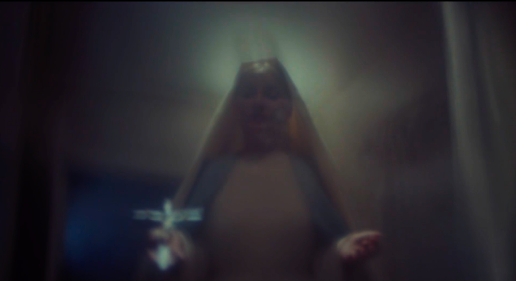 blurry POV from Maureen’s point of view in the bathtub of Mary looking down on her in peace, holding a crucifix in her right hand. The view is blurry because of Maureen’s suicide attempt. It’s actually Norman Bates standing over her holding a knife.