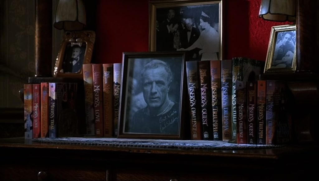 a framed photo of a white man with eight books shelved on both sides of the picture frame