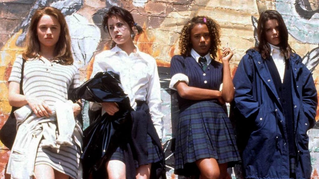 Four teenage girls stand in front of a painted wall.