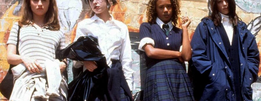 Four teenage girls stand in front of a painted wall.