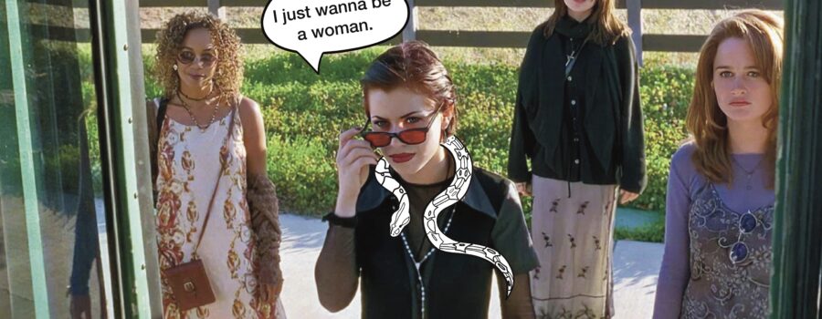 Still from The Craft (1996, directed by Andrew Fleming): four young fem presenting people are framed by a bus door. Behind them is a field. The person in the center of the frame has a snake loosely around her neck and a speech bubble that reads, “I just wanna be a woman.”
