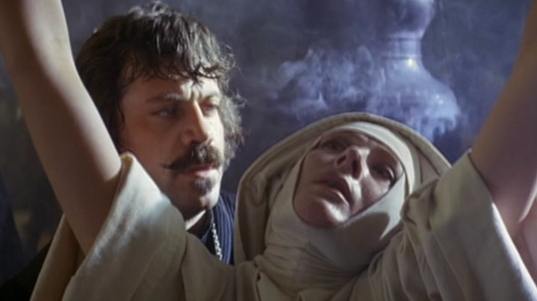 Father Urbain Grandier (Oliver Reed) speaking to Sister Jeanne (Vanessa Redgrave) amidst one of her torture sessions.